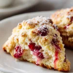 single cranberry orange scone torn open to reveal soft fluffy crumb inside